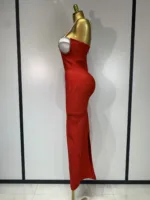 A gold mannequin showcases the Crystal Bust Long Bodycon Dress—a fitted, strapless red gown with a side slit, pearl detailing around the bust, and a smooth silhouette—set against a plain backdrop with light-colored panels.