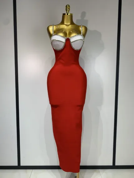 A gold mannequin showcases the Crystal Bust Long Bodycon Dress, a form-fitting, strapless red midi with a white, crystal-embellished bustier top. The dress creates an hourglass silhouette and is set against a plain white background.