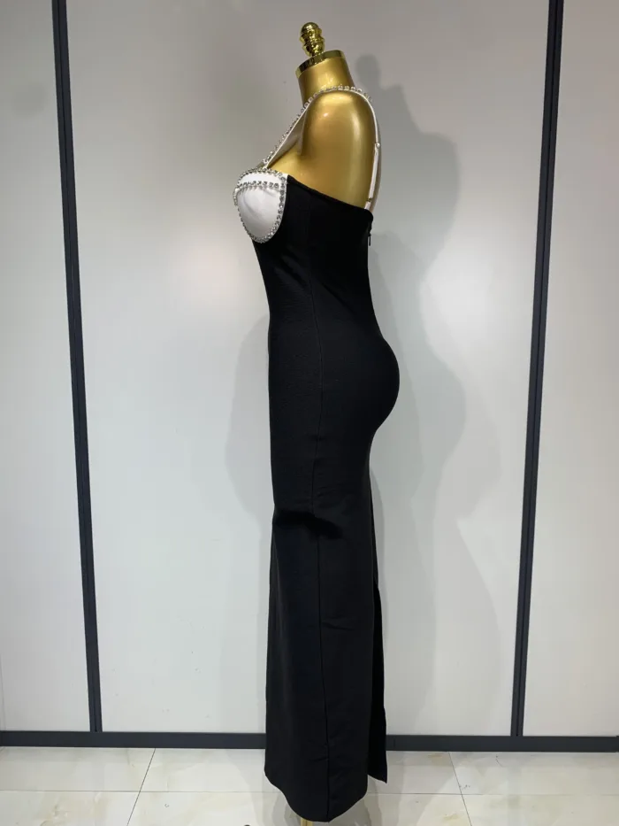 A gold mannequin, seen in profile against a light background, models the Crystal Bust Long Bodycon Dress—a strapless black gown featuring a white crystal-studded bust.