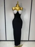 A gold mannequin showcases the Crystal Bust Long Bodycon Dress, featuring a form-fitting black skirt and a white, beaded bustier top. The background is a plain light wall with vertical black trim.