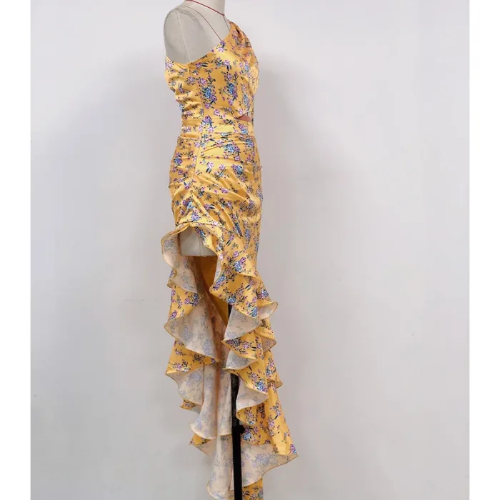 The Hollowed-Out Hip Irregular Ruffled Floral Dress features a yellow floral satin design, spaghetti straps, a fitted bodice, and a cascading ruffled high-low hem, shown on a mannequin against a plain white background.