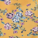 A close-up of the Hollowed-Out Hip Irregular Ruffled Floral Dress shows yellow fabric with pink, white, and blue flowers and green leaves scattered across the surface.