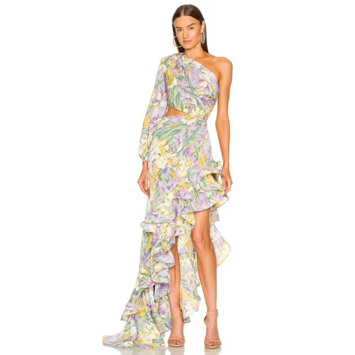 A woman models the Hollowed-Out Hip Irregular Ruffled Floral Dress, featuring a pastel floral one-shoulder design with an asymmetrical hem and waist cutout, styled with strappy nude heels and statement earrings against a white backdrop.
