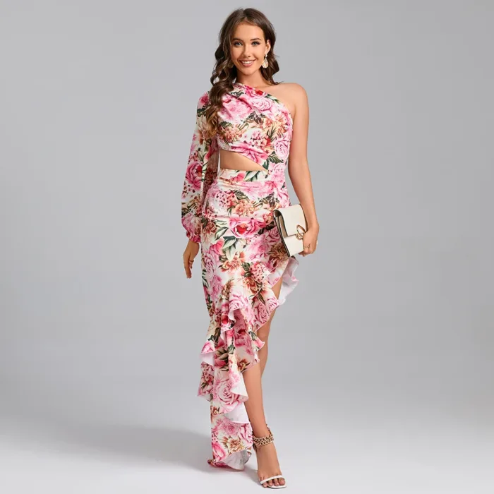 A woman models the Hollowed-Out Hip Irregular Ruffled Floral Dress, featuring florals, ruffles, and a side cutout. She poses against a gray background, holding a beige clutch and wearing strappy heels with a bright smile.