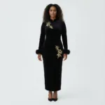 A woman wearing long sleeved embroidered dress featuring intricate floral patterns, fitted waist maxi dress,