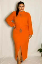 A plus-size model poses confidently in a vibrant orange chiffon and crepe dress with crystal embellishments, standing against a white backdrop.