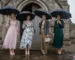 Women in wedding guest outfits with umbrellas